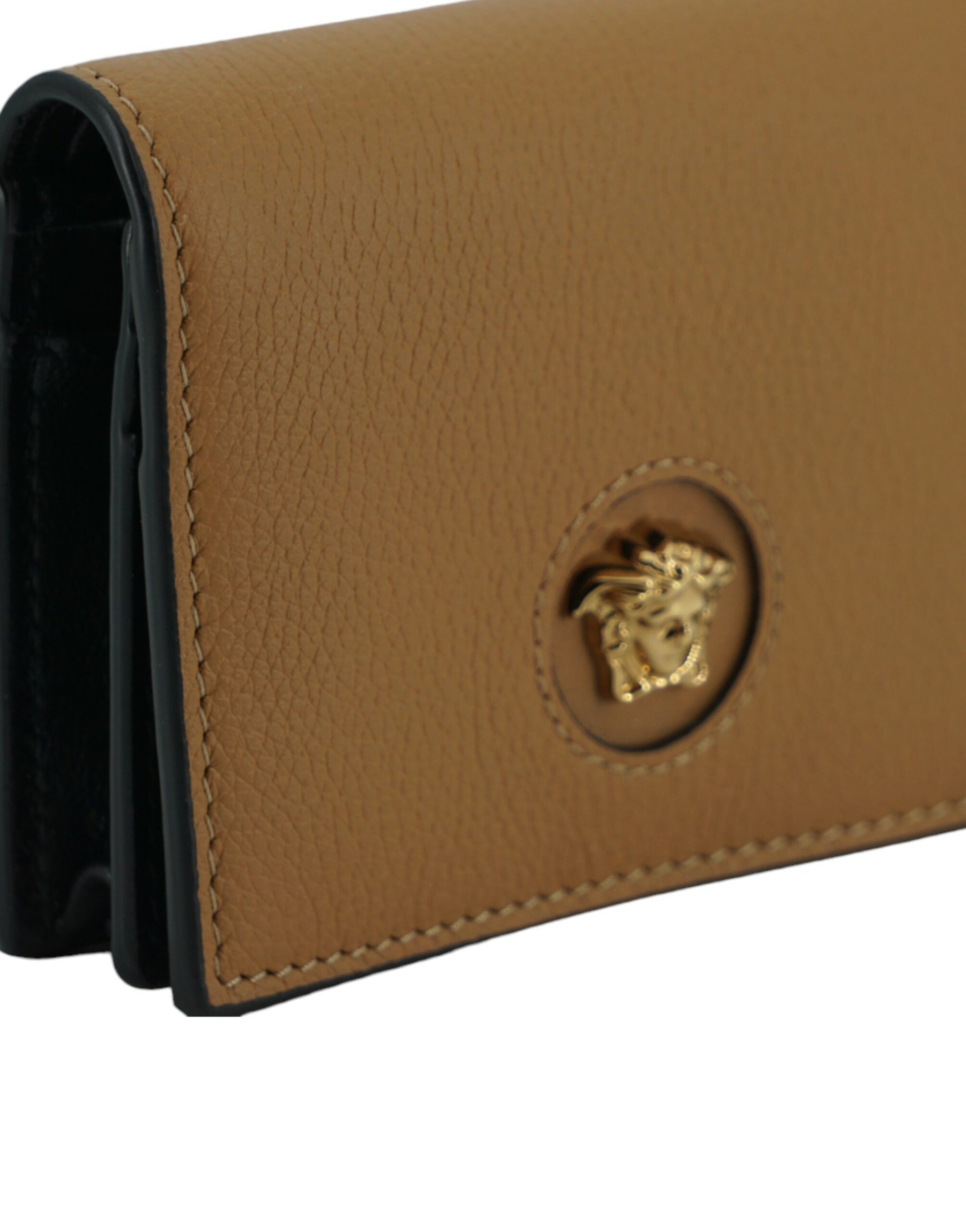Close-up of tan leather wallet with gold Medusa head emblem and detailed stitching