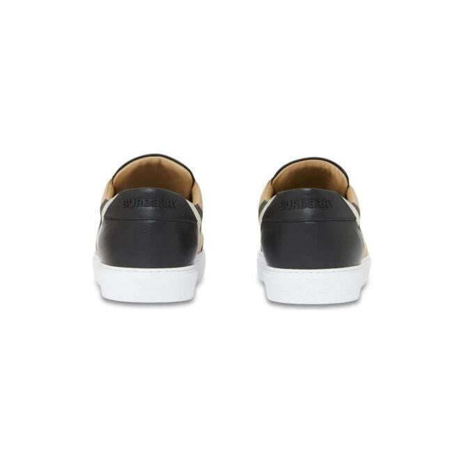 Rear view of Burberry sneakers with black heel panels and white soles on white background