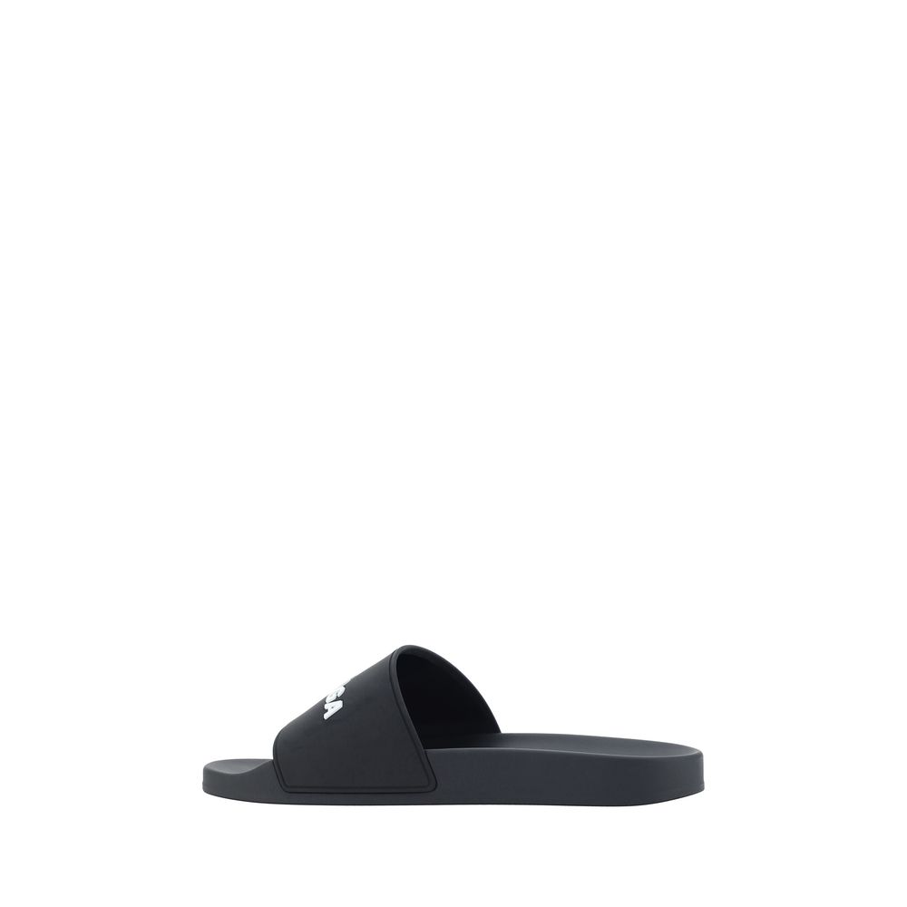 Black Balenciaga slide sandal with white logo on wide strap, side view on white background
