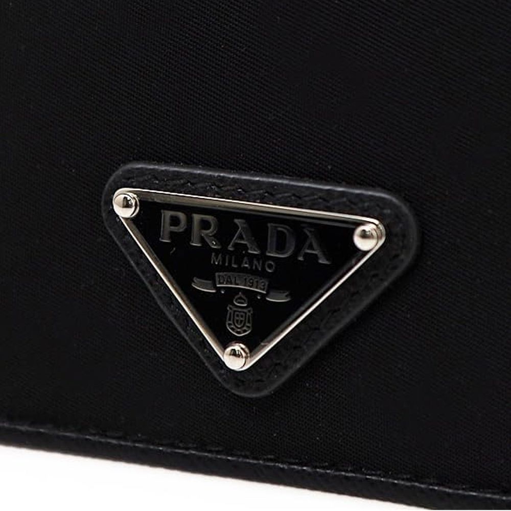 Close-up of black Prada Milano triangle logo plaque on fabric bag with silver accents
