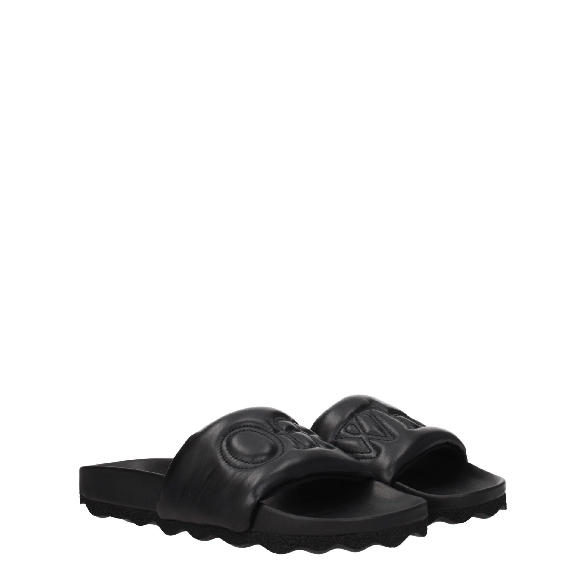 Pair of black slide sandals with embossed logo and textured sole on white background