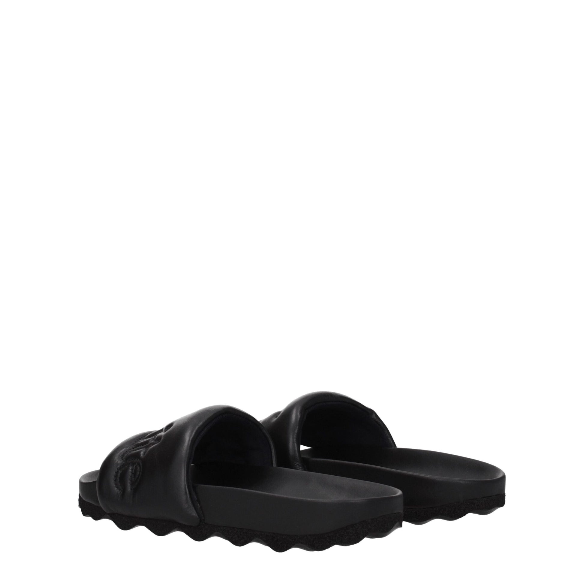 Black leather slide sandals with padded straps and wave-patterned soles on white background