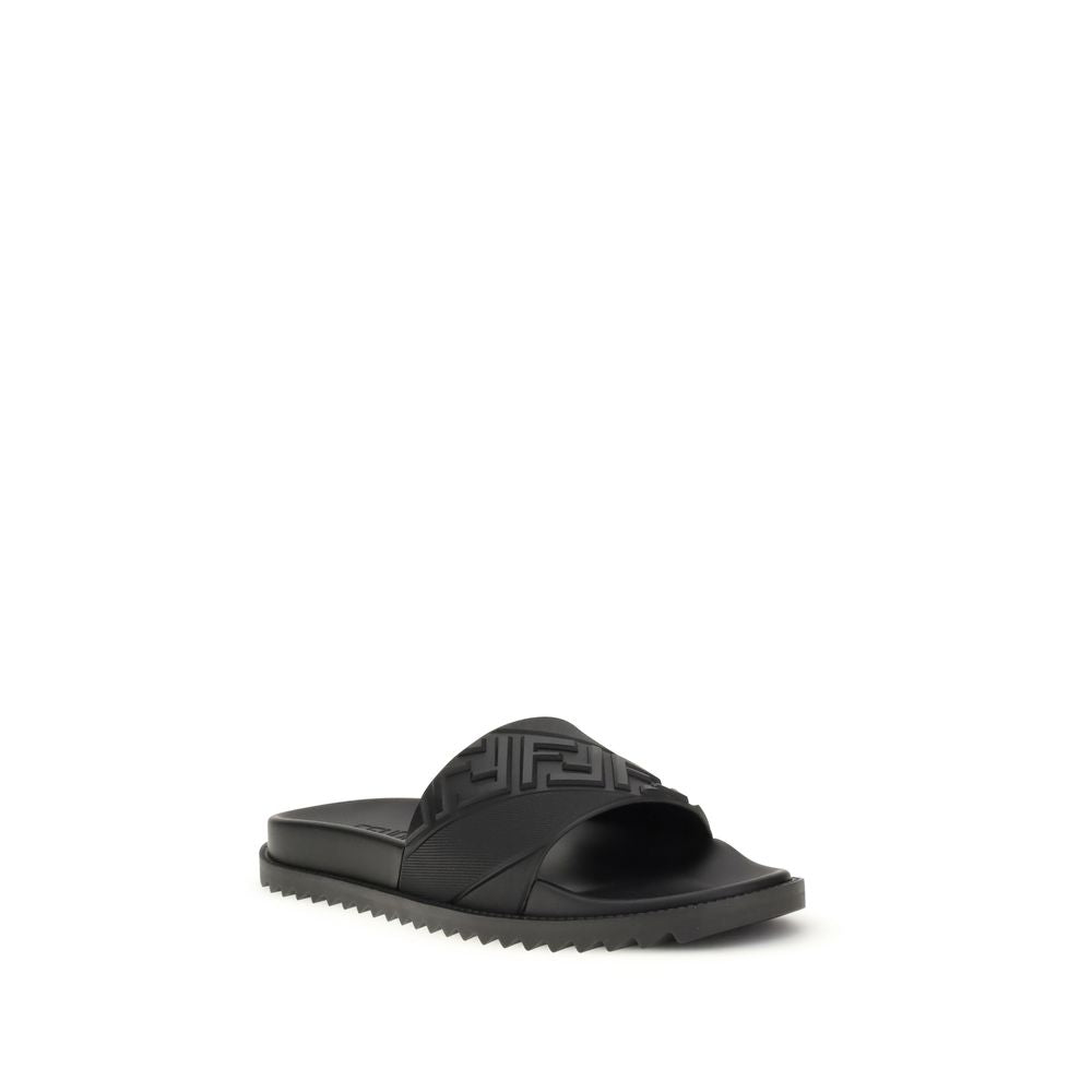 Black slide sandal with textured strap and serrated sole on white background